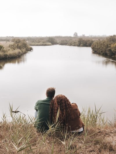 vista-posterior-pareja-sentada-junto-estanque